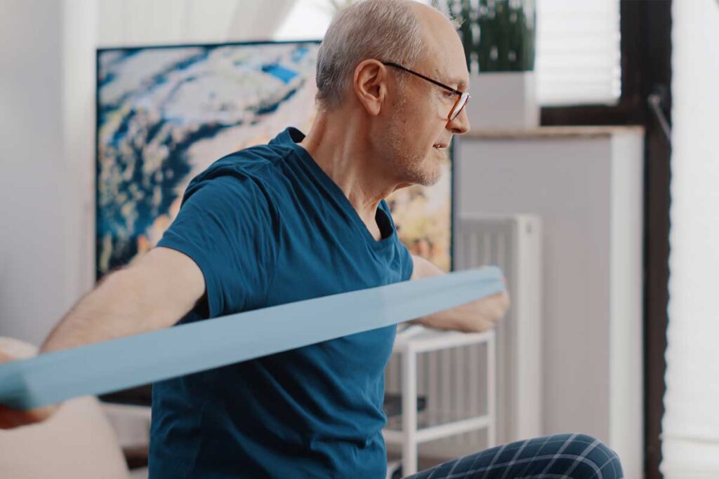 Starijim muškarac radi vežbe sa gumenom trakom